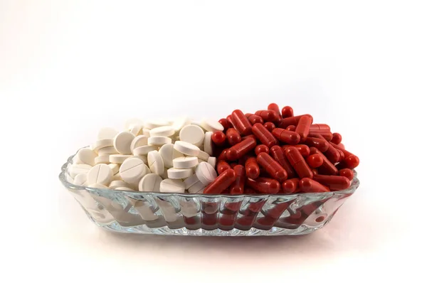 赤カプセル充填薬 白い背景の上にすべての白い丸い錠剤と他のと半分で満たされた透明なガラスのプレート — ストック写真