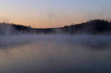 Sabah erken saatlerde gölde, sis su yüzeyine, gökyüzünün yansıması ve bitkiler üzerinde karşı kıyıda.