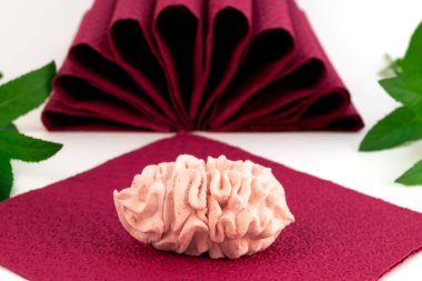 A yelpaze-in bard kağıt peçete yeşil nane yaprakları ile arka plan üzerinde iki yarısı gelen pembe şekerleme.