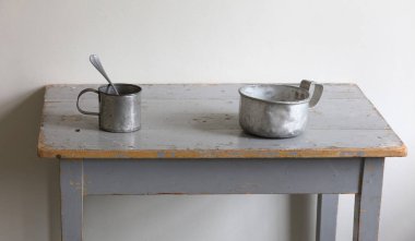 Çok eski metal bardak ve tabaklar ahşap bir masa üzerinde