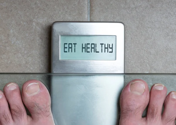 Iemands voeten op gewicht schaal - gezond eten — Stockfoto