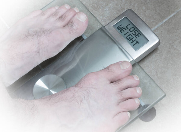 Man's feet on weight scale - Lose weight