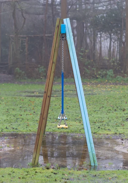 Plastic swing hanging over a puddle — Stock Photo, Image