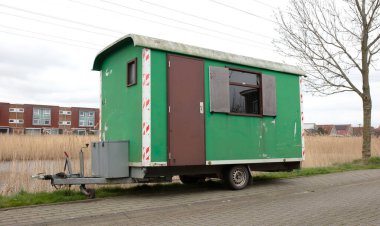 Tekerlekli eski yeşil ahşap römork yol kenarında duruyor, Hollanda.