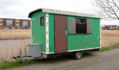 Tekerlekli eski yeşil ahşap römork yol kenarında duruyor, Hollanda.