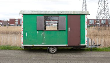 Tekerlekli eski yeşil ahşap römork yol kenarında duruyor, Hollanda.