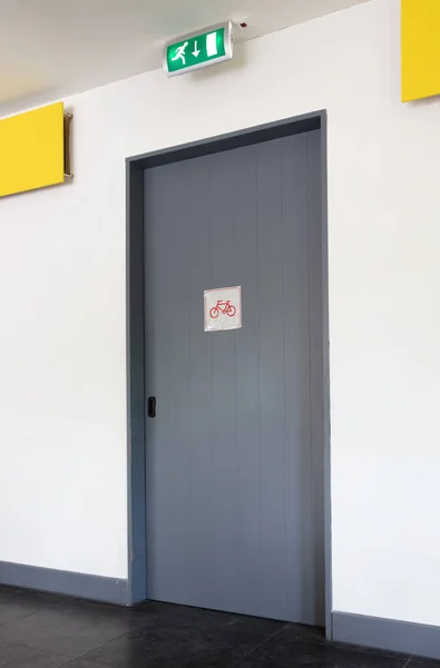 Emergency exit wooden door with tablet above it, also a garage for bicycles