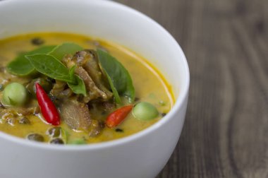 Ahşap arka plan üzerine bir kase içinde Hindistan cevizi sütü ile domuz eti köri