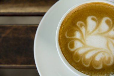 Ahşap arka plan üzerinde beyaz bir fincan Cappuccino kahve