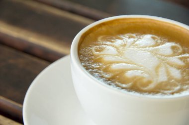 Ahşap arka plan üzerinde beyaz bir fincan Cappuccino kahve