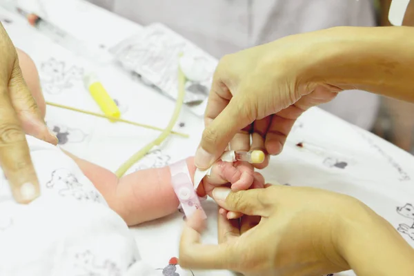 护士的手是刺伤注射插头 注射或后充满盐水 用医用胶带将针头附在婴儿手上 — 图库照片