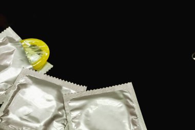 Prezervatif gümüş paketlerinde ve bir bitkileri açıldı ve siyah arka plan üzerine alan izole duyuyor musun.