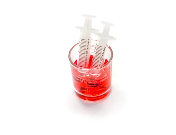 医学用红色液体药物测量玻璃杯用塑料注射器准备进入患者的嘴隔离在白色背景和做用路径 — 图库照片