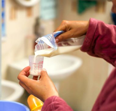 Hemşirenin ellerini annemin taze süt süt depolama için plastik torba hastanede hasta yeni doğan bebek için ilaç ölçüm cam fincan için dökme.