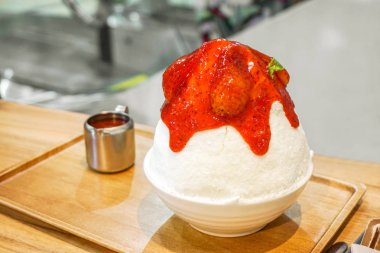 Bingsu çilek (dondurulmuş inek sütü olun kar pul için iplik ve çilek şurubu ile tepesinde.) (Tatlı Kore.) ahşap tepsi ve masa Kupası kafede paslanmaz ile beyaz seramik kase.