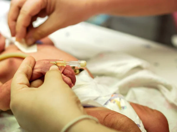 护士手是刺注射插头在生病新生儿的手准备填充盐水溶液和药物 — 图库照片
