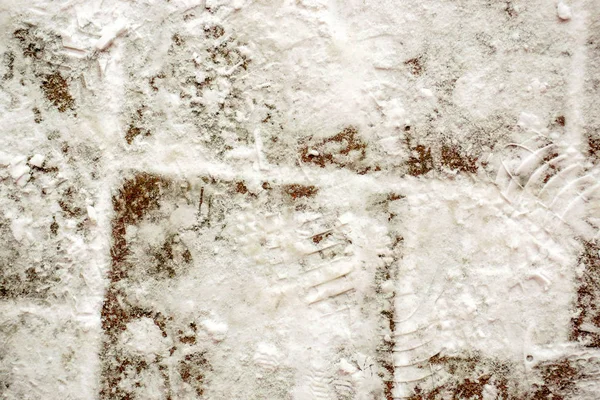 Image of snow and ices with texture of shoe and sneakers soles covered on brick floors background.