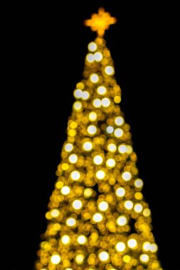Yılbaşı ağacı ve siyah arka planda bulanık ve noel aydınlatması.