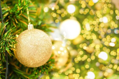 Noel günü Çam Ağacı 'nda süslenmiş Altın Noel Baloları bulanık bir arka plan ve Noel ışıklandırması ile.