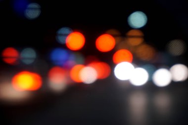 Bulanık ve Bokeh yansıması arabaların trafik ışıklarının şehrin gece vakti yankılanmasıyla birlikte yol ışıklarının yanması..