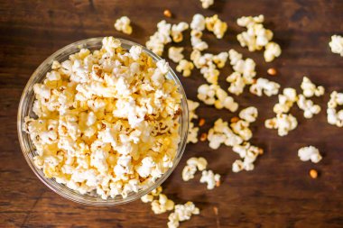 Cam bir fincanda patlamış mısırın en üst görüntüsü. Tahta bir masada patlamış mısır..