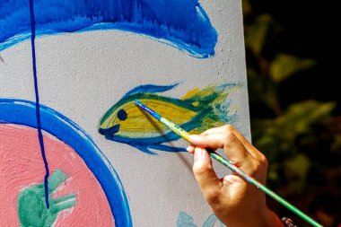 Lampang, Tayland, 28 Haziran 2019: Fırça tutan sanat öğrencilerinin eli yeni sanat sınıfı duvarını çiziyor ve dekore ediyor.