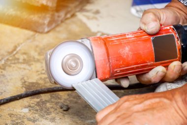 Elektrik açı öğütücüsünü tutan işçinin yakın çekim elleri inşaat sahasında çalışıyor..