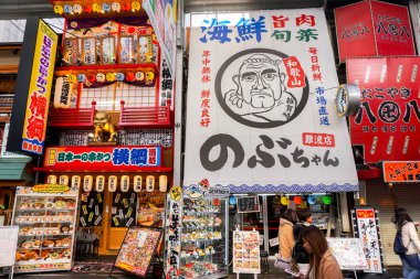 Osaka, Japonya, 16 Ocak 2019 Osaka alışveriş caddesinde altın çocuk tanrı Billy Ken ile Japon restoranının benzersiz ve renkli tabelası..