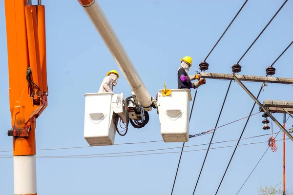 在浅蓝色天空背景下修理电力线的电缆车的电工 — 图库照片