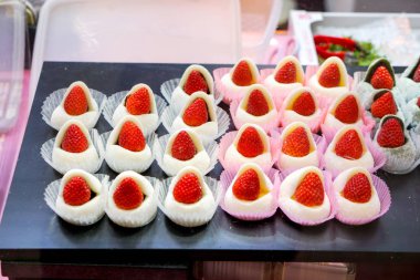Kuromon caddesindeki markette satılan siyah tepside çilek dolu büyük mochi. Turistleri satın almaya davet eden renkler ve şekiller.
