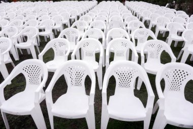 Mezuniyet töreninde öğrenciler için sıralı üzerine oturtun ve kırpma beyaz plastik sandalyeler.