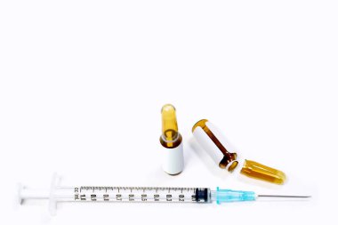 3 ml. Kahverengi ilaç ampulleri açılır ve beyaz zemin üzerinde tıbbi iğne bulunan plastik şırıngalar.