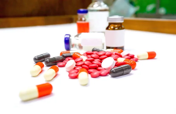 白いテーブルの上に赤い錠剤の薬とカプセルの場所の閉じ込めアンプルぼやけた背景 — ストック写真