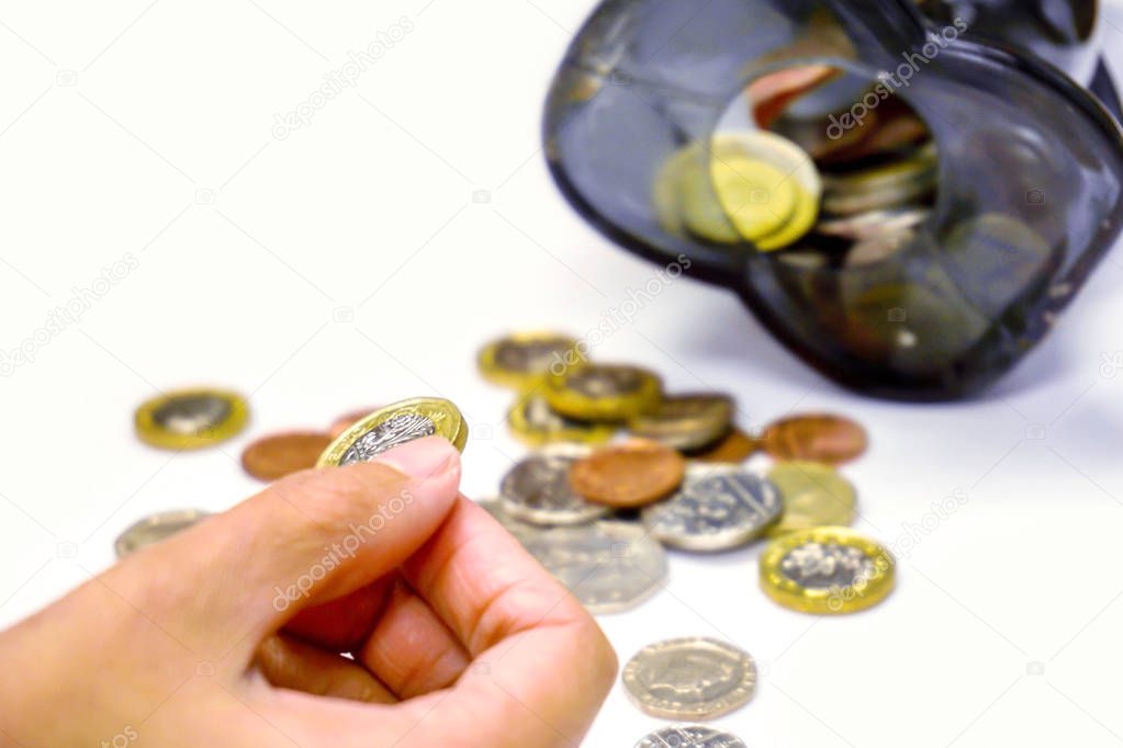 Image of hand picking up a new one pound British currency coins 