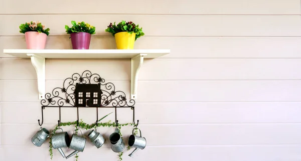 白い棚の上に3つの鍋に花と白い木製の壁の背景に装飾小さなシャワーを掛けます — ストック写真