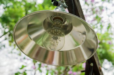 Yakın plan klasik lamba ahşap direğe asılı ve bulanık yeşil doğa arka planı