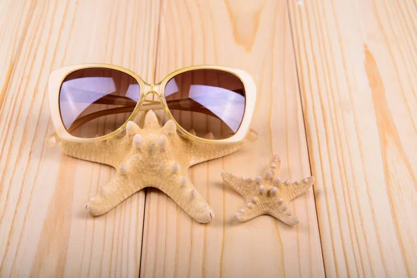 Óculos de sol e estrelas do mar em um fundo de madeira — Fotografia de Stock