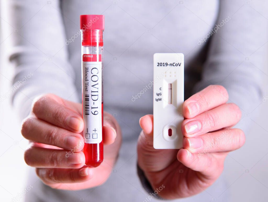 Rapid Covid-19 coronavirus strip test cassette for antibody or sars-cov-2 virus disease and blood test tube in hands epidemic concept background close-up