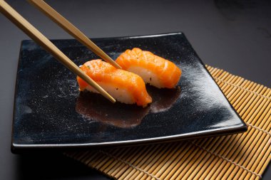 Suşi, maki ve Amerikan dürümlü siyah tabak.