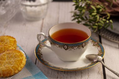 Beyaz ahşap bir masada bisküvili bir fincan çay