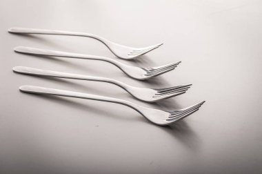 Pek çok parlak gurme restoran kalitesinde gümüş çatallar beyaz bir yemek masasının üzerine yerleştirilmiş. Çatal bıçak, mutfak çatal bıçak ve gıda endüstrisi kavramı..