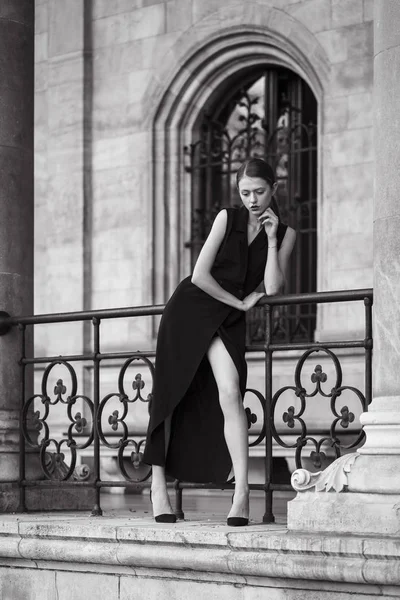 古典主義建築の前に黒のドレスを着た若い女性のファッションの肖像画 — ストック写真