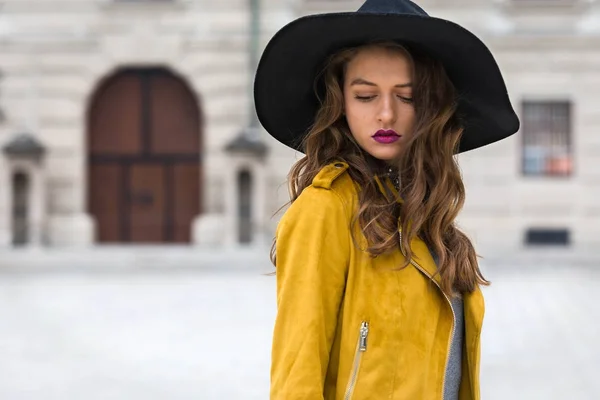 Estilo de vida retrato de uma jovem mulher vestindo jaqueta de couro amarelo e chapéu preto — Fotografia de Stock