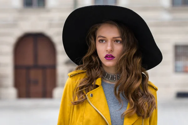 Estilo de vida retrato de uma jovem mulher vestindo jaqueta de couro amarelo e chapéu preto — Fotografia de Stock