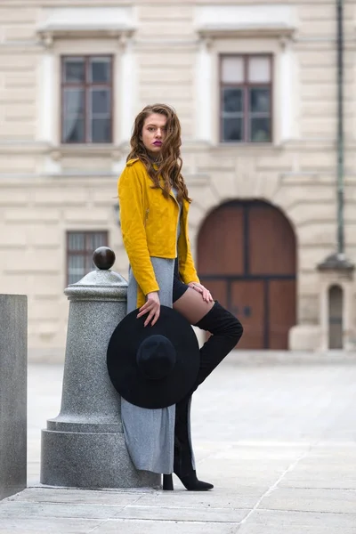 Estilo de vida retrato de uma jovem mulher vestindo jaqueta de couro amarelo e botas de joelho — Fotografia de Stock