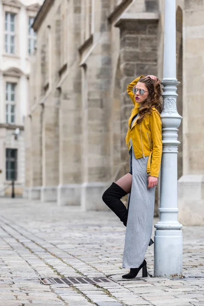 Lifestyle πορτρέτο μιας νεαρής γυναίκας που φοράει κίτρινο δέρμα σακάκι και overknee μπότες — Φωτογραφία Αρχείου
