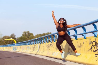 Genç Afrikalı Bayan spor giyim giymek ve sokakta müzik dinlemek