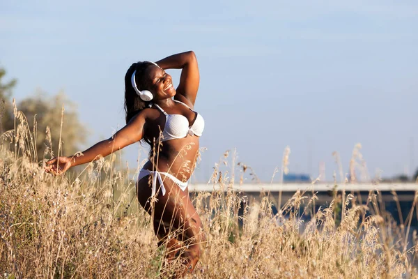 Hermosa mujer africana con bikini y escuchando música en verano — Foto de Stock