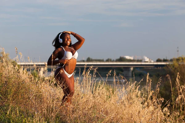 Hermosa mujer africana con bikini y escuchando música en verano — Foto de Stock