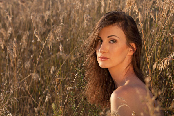 Closeup portrait of an attractive young woman sitting in the green